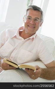 Man in living room reading book smiling