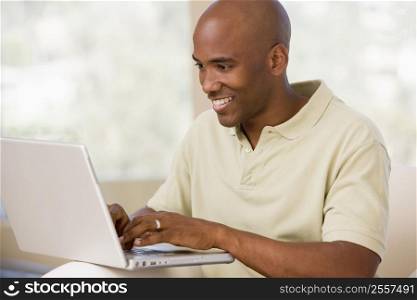 Man in living room using laptop and smiling