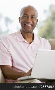 Man in living room using laptop and smiling