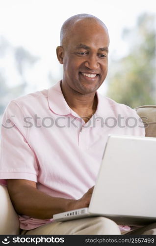 Man in living room using laptop and smiling