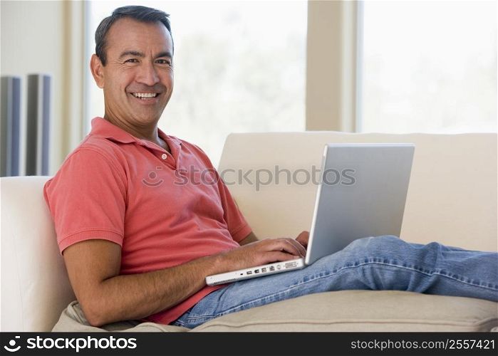 Man in living room using laptop smiling