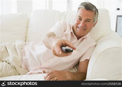 Man in living room using remote control smiling