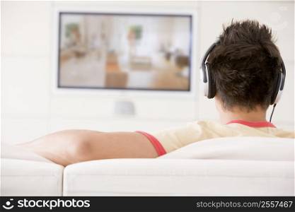 Man in living room watching television and wearing headphones
