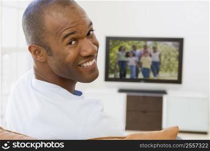 Man in living room watching television smiling