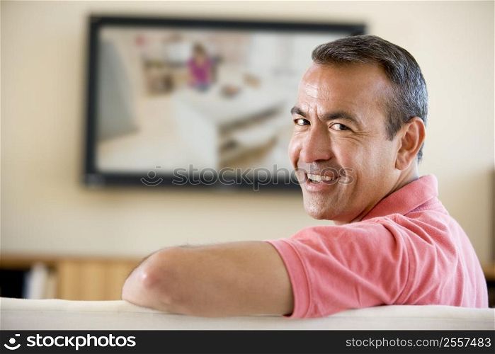 Man in living room watching television smiling