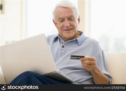 Man in living room with laptop and credit card smiling