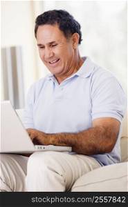 Man in living room with laptop smiling