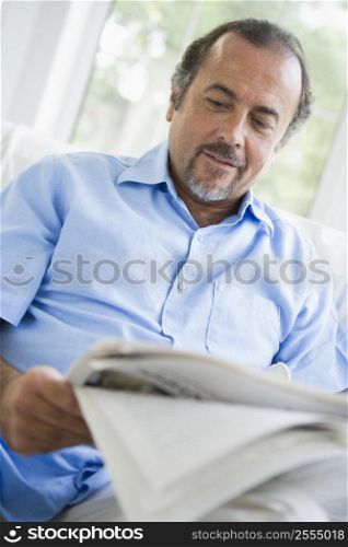 Man in living room with newspaper (high key/selective focus)