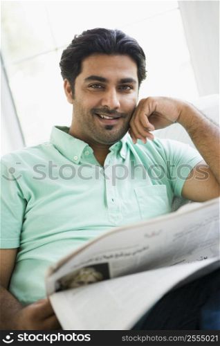 Man in living room with newspaper smiling (high key/selective focus)