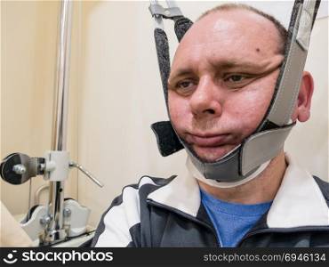 Man in neck traction machine for physiotherapy