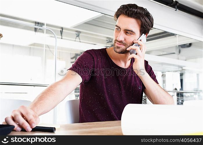 Man in office using mobile phone, looking away
