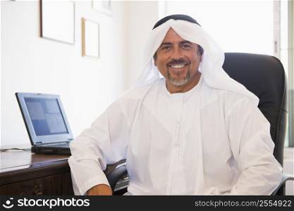 Man in office with laptop smiling (high key/selective focus)