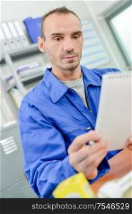 Man in overalls looking at notepad
