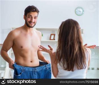Man in oversized pants in weight loss concept with girlfriend wife. Man in oversized pants in weight loss concept with girlfriend wi