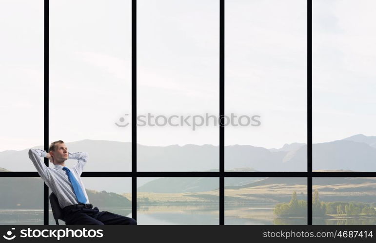 Man in panoramic office. Relaxing businessman with crossed hands behind his head in office