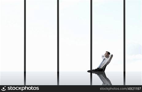 Man in panoramic office. Relaxing businessman with crossed hands behind his head in office