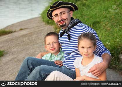 man in pirate suit with his son and daughter near pond in early fall park