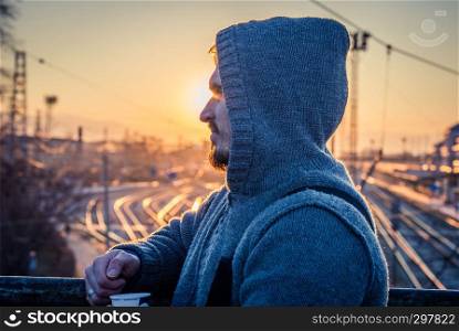 Man in profile with hoodie railway background
