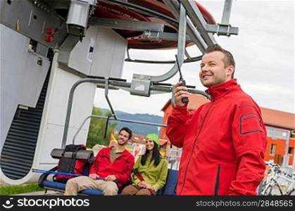 Man in red coat using radio starting chair lift