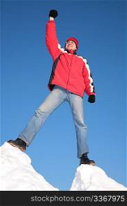 man in red jacket on top of snow hill with hand up