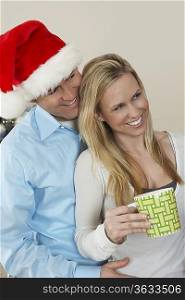Man in Santa hat with arm around woman with coffee cup