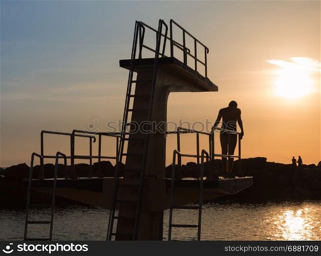 Man in Silhouette Hesitating in Jumping from High Board into Water