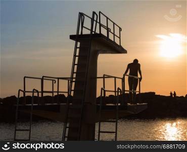 Man in Silhouette Hesitating in Jumping from High Board into Water