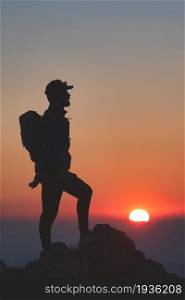 Man in silhouettes on top of a mountain at sunset