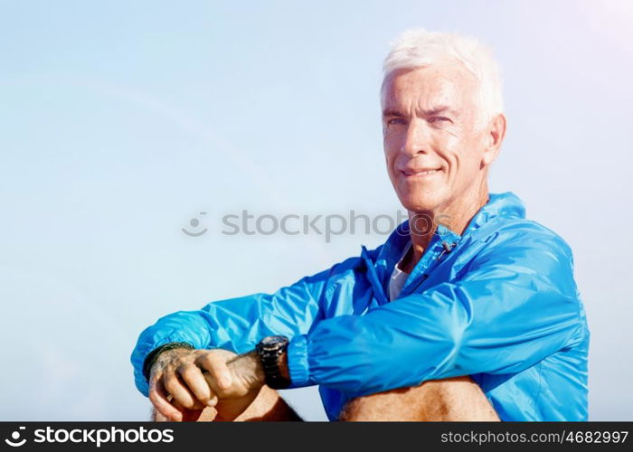 Man in sports wear sitting at the beach. Man in sports wear sitting alone at the beach and having minute of rest