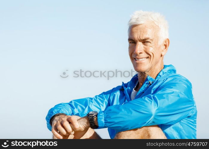 Man in sports wear sitting at the beach. Man in sports wear sitting alone at the beach and having minute of rest