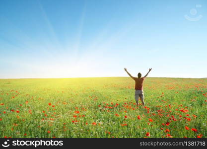 Man in spring meadow of poppy reach to sky. Happy emotional religion and conceptual scene.