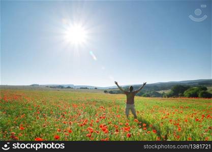 Man in spring meadow of poppy reach to sun. Happy and emotional religion scene.