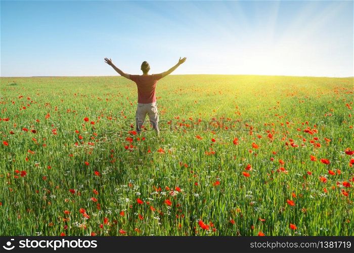Man in spring meadow of poppy reach to sun. Happy emotional religion and conceptual scene.