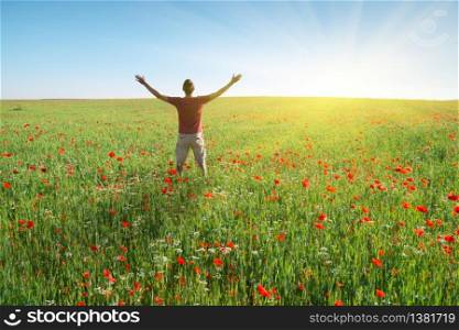 Man in spring meadow of poppy reach to sun. Happy emotional religion and conceptual scene.