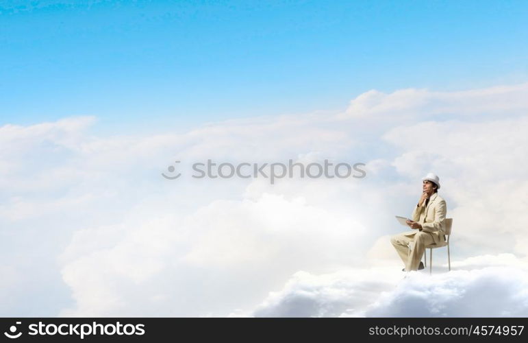 Man in suit and hat use tablet. Young businessman sitting in chair and using tablet