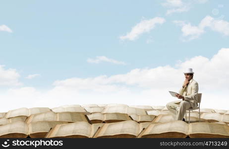 Man in suit and hat use tablet. Young businessman sitting in chair and using tablet