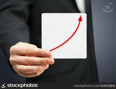 man in suit holding card with increasing graph on it