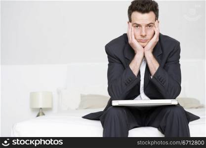 man in suit sitting on bed with laptop