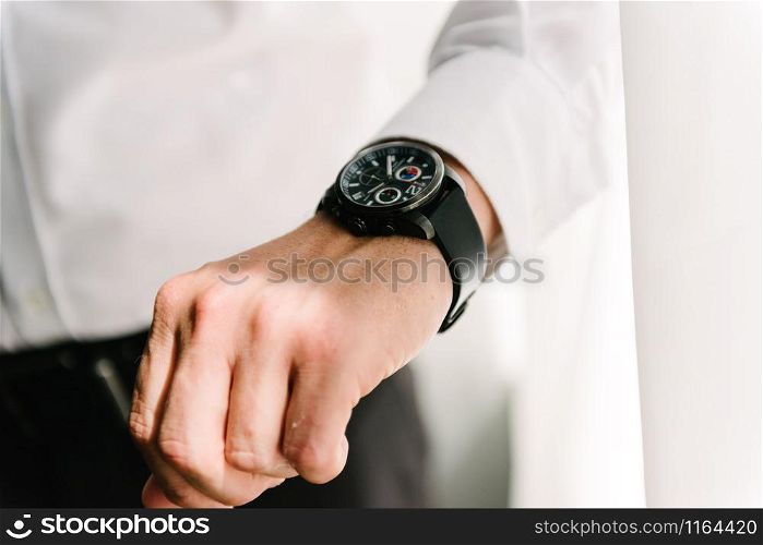 Man in suit straightens shirt sleeve close up. Man in suit with hand adjusts sleeve of shirt close-up