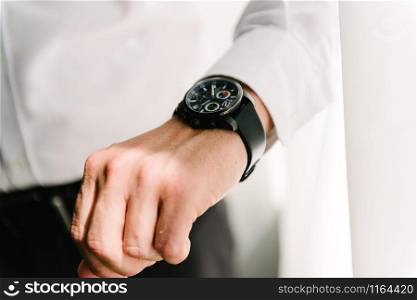 Man in suit straightens shirt sleeve close up. Man in suit with hand adjusts sleeve of shirt close-up