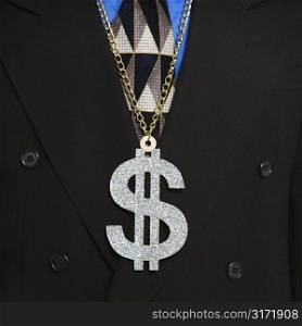 Man in suit wearing necklace with money sign.