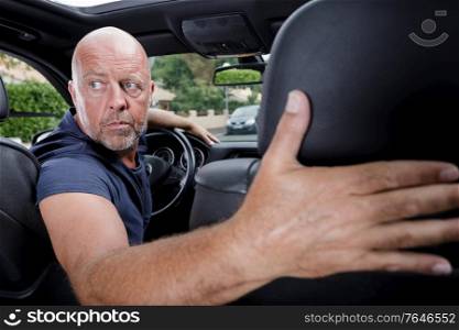 man in the car turns backwards