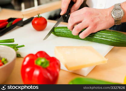 Man in the kitchen ? only torso to be seen ? is preparing the vegetables for dinner or lunch