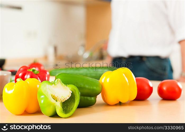 Man in the kitchen ? only torso to be seen ? is preparing the vegetables for dinner or lunch