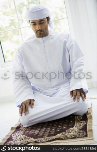 Man in turban praying on mat (high key)