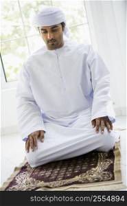 Man in turban praying on mat (high key)
