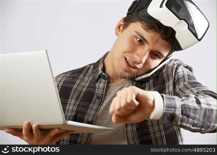 Man In Virtual Reality Headset Looking At Smart Watch And Talking On Mobile Phone