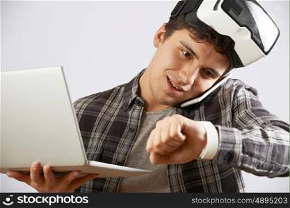 Man In Virtual Reality Headset Looking At Smart Watch And Talking On Mobile Phone