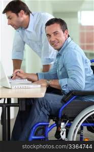 Man in wheelchair at desk working next to colleague