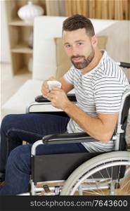 man in wheelchair drinking coffee indoors